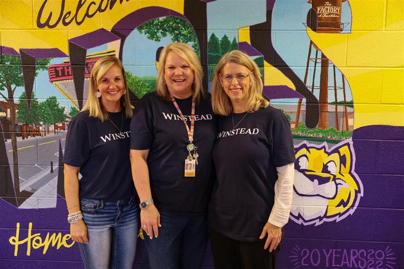 Teachers stand in front of a mural